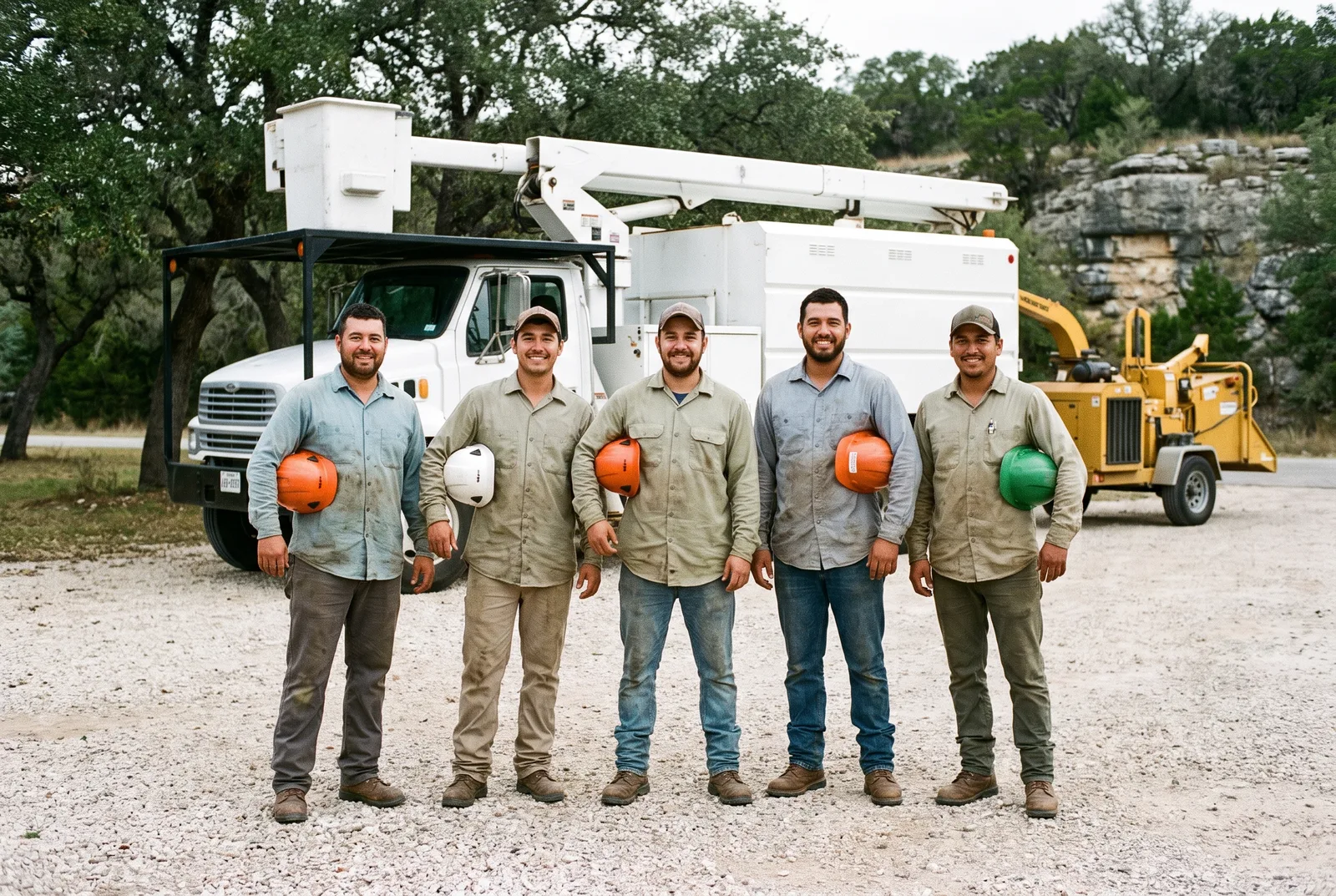The Georgetown Tree Co. crew in front of their bucket truck and chipper on a gravel lot under live oaks